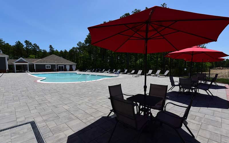 Image of pool, clubhouse, and table with red umbrellas